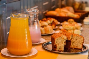 Un buffet de petit-déjeuner avec un assortiment de viennoiseries et un verre de jus d’orange.