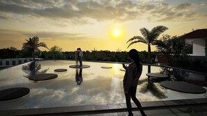 A reflective pool with circular platforms, palm trees, and a sunset in the background. - THE NEST ISHIGAKI (Ishigaki)