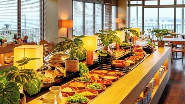 A buffet with various food items and plants, a bar area, and a view through large windows. - THE NEST ISHIGAKI (Ishigaki)