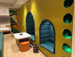 Habitación de hotel moderna con sofá, una mesita y un cubo de basura.