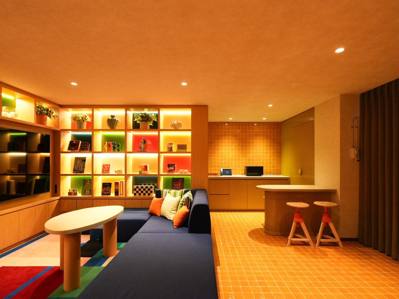 A modern living room with a sofa, a coffee table, and a kitchen area with a counter and stools.