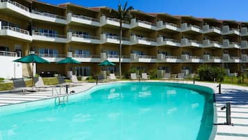 Un hotel con piscina, varios balcones y zonas de estar al aire libre.