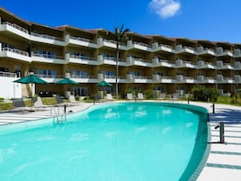 Un hotel con piscina, varios balcones y zonas de estar al aire libre.