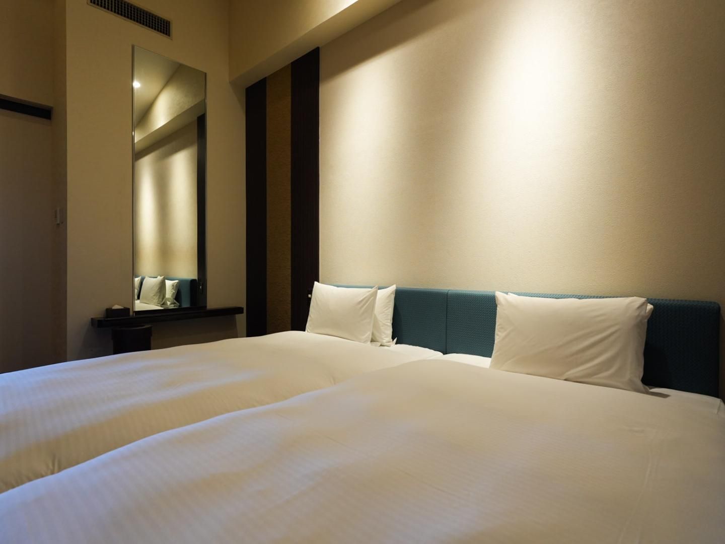 A hotel room with a large bed, a mirror, and a wall with vertical stripes.