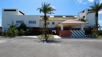A hotel with a modern design, featuring a flat roof, a central entrance, and a parking lot.