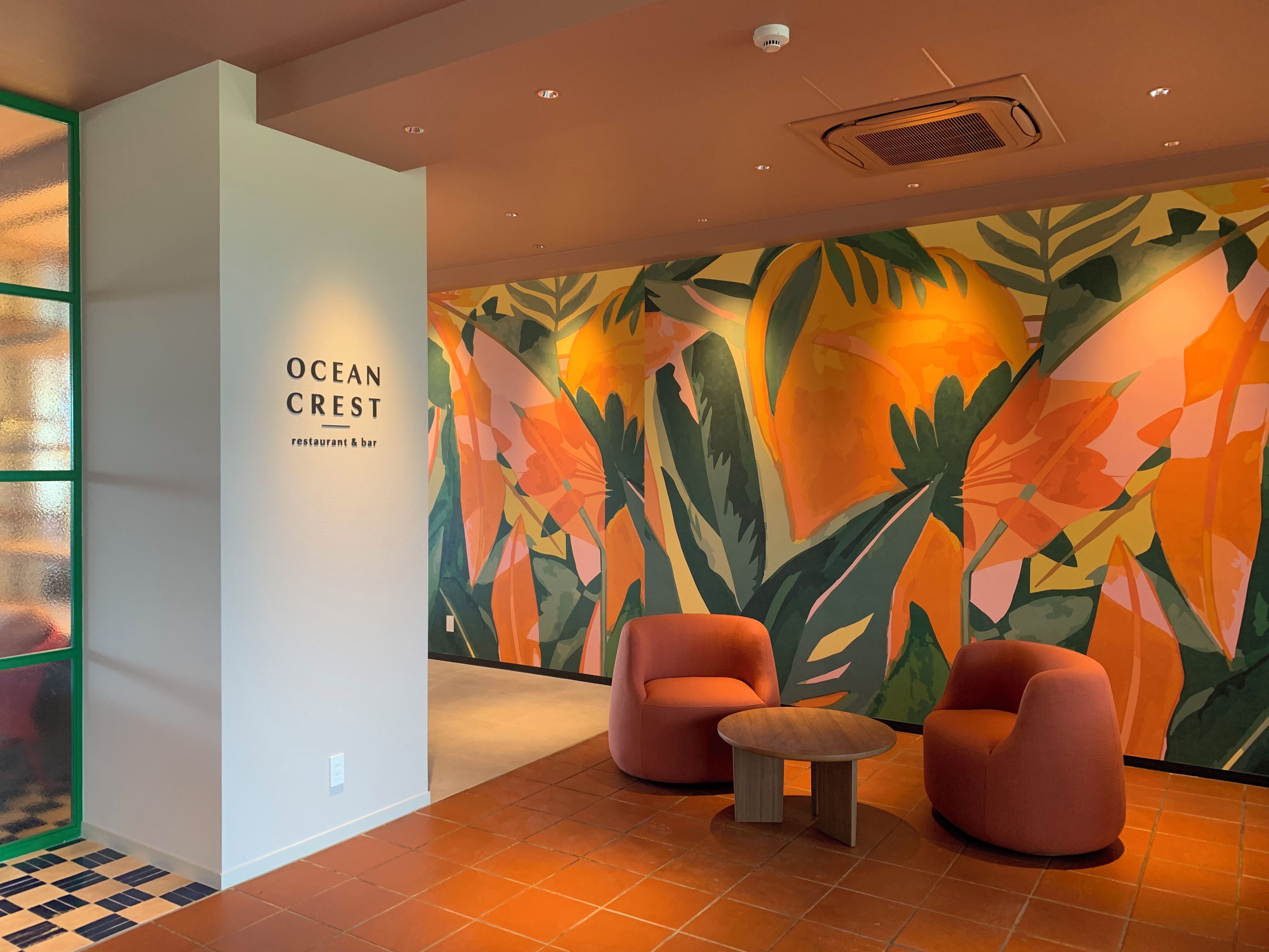 A modern interior with a wall mural, two orange chairs, and a small round table.