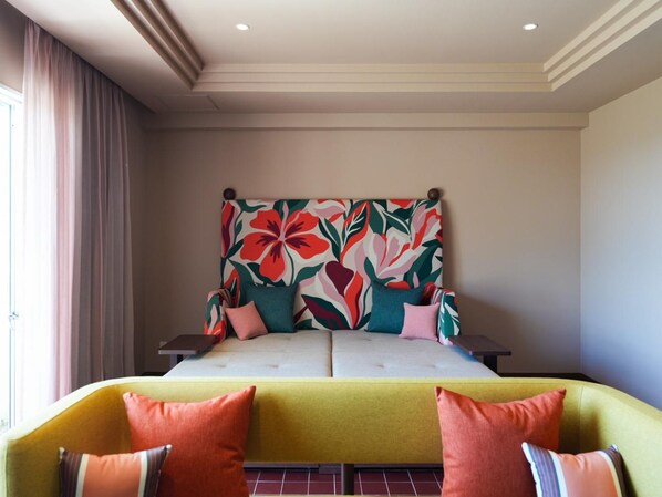 Ein Hotelzimmer mit einem Bett, einem gelben Sessel und einem großen Kopfteil mit Blumenmuster.