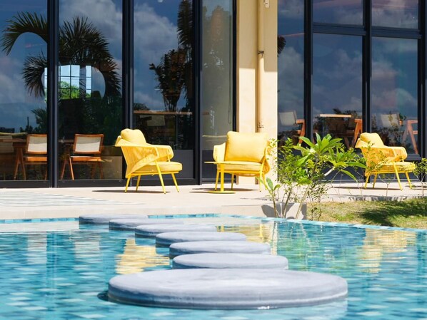 A pool area with yellow chairs and a clear view of the sky through large windows.