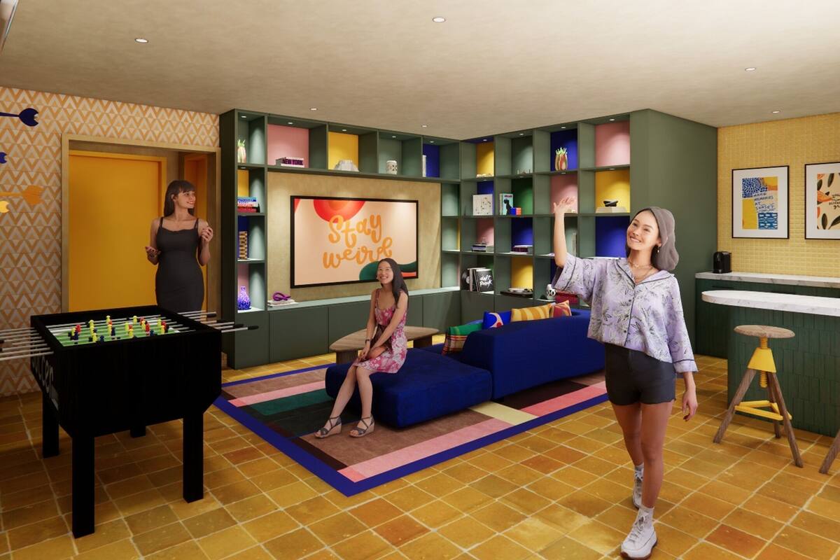A room with a foosball table, a sofa, a bar area, and a wall with a 'Stay Weird' poster.