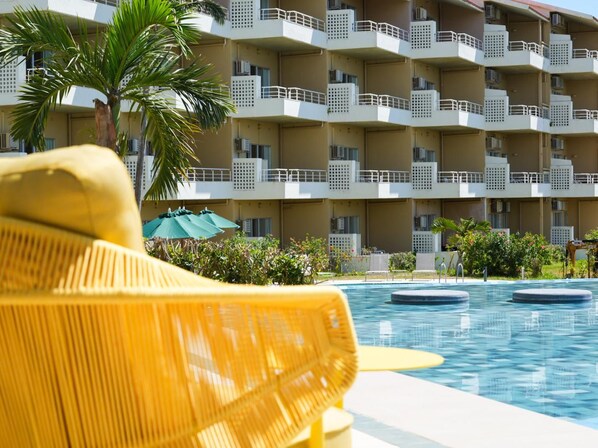 A hotel with multiple balconies, a swimming pool, and outdoor seating.