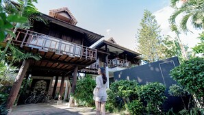 A two-story building with a balcony, surrounded by lush greenery.