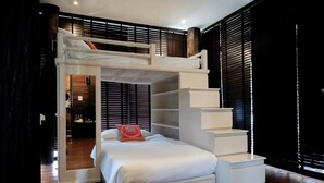 A modern bedroom with a bunk bed, built-in shelving, and a staircase.