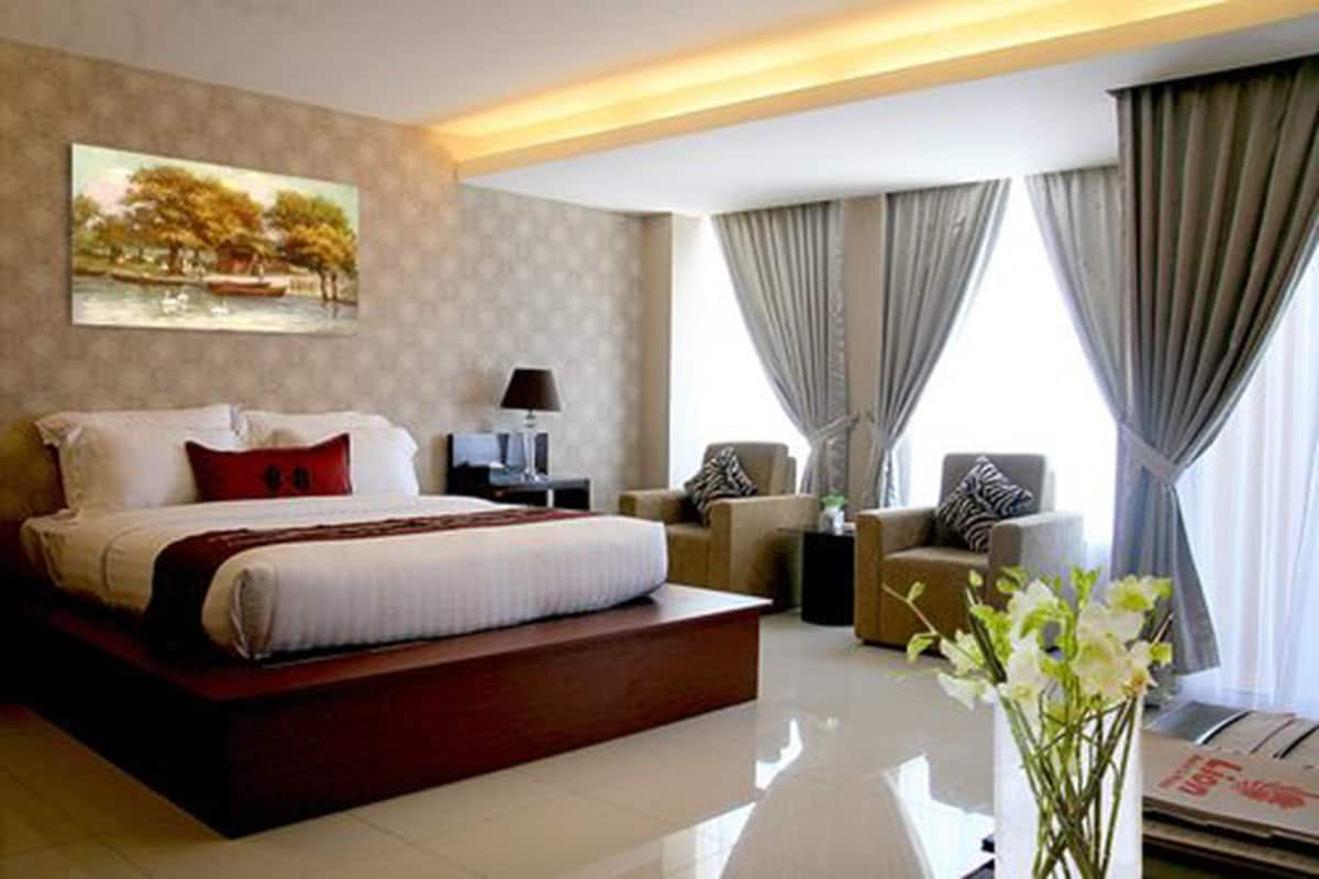 A modern hotel room with a large bed, a desk, a chair, and a view of the outdoors through the window.