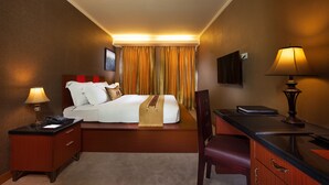 A hotel room with a bed, bedside table, desk, chair, and a TV on the wall. - Lion Hotel & Plaza (Manado)