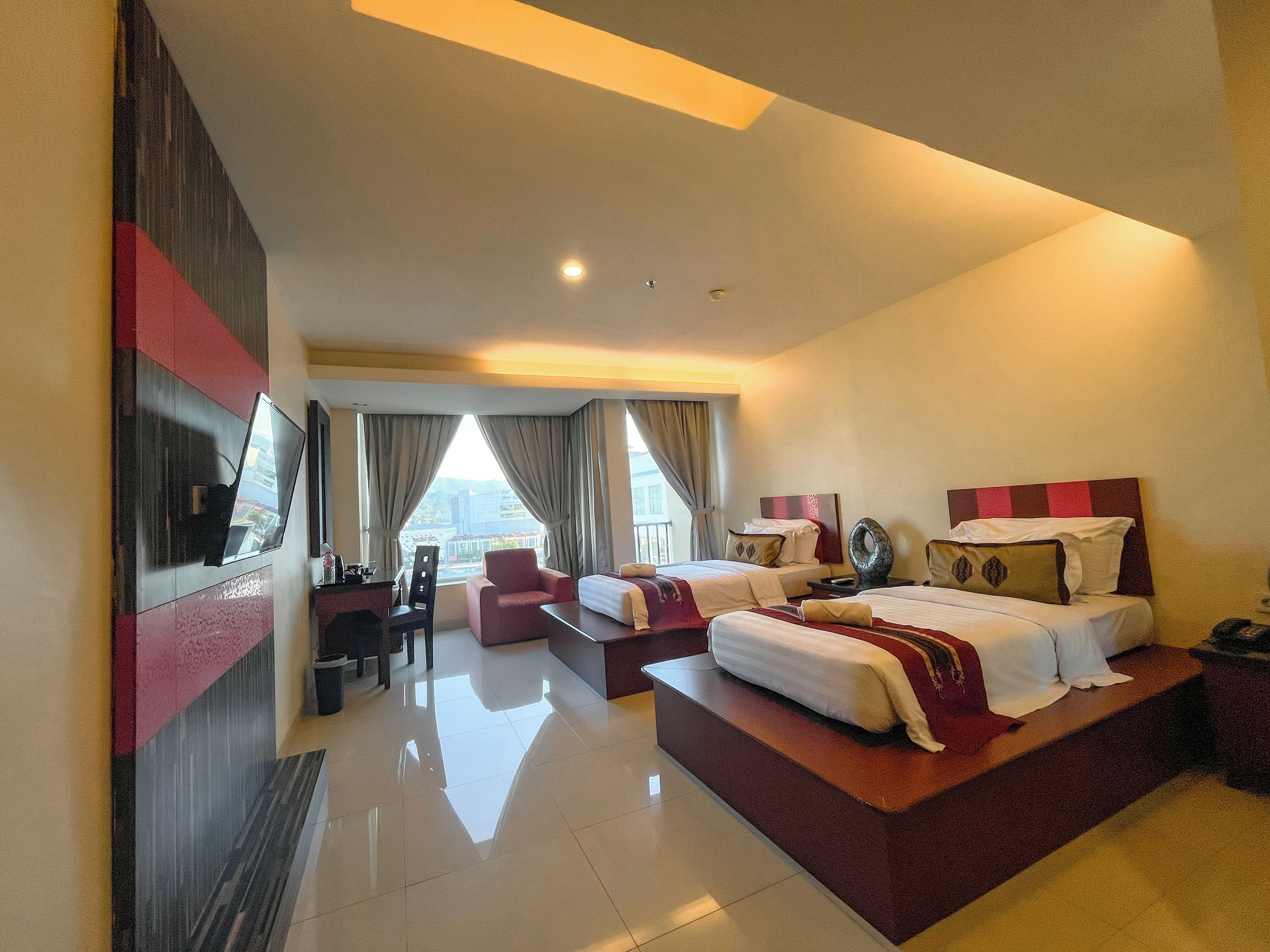 A hotel room with a large bed, a desk, a chair, and a TV.