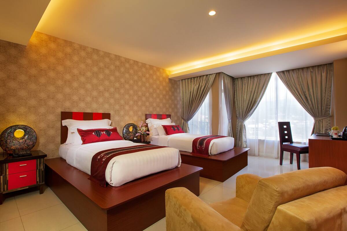 A hotel room with two beds, a desk, and a chair.