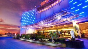 El exterior del Lion Hotel & Plaza, con un diseño moderno, presenta un letrero llamativo y una fachada bien iluminada.