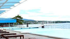 A covered outdoor area with lounge chairs and a pool.