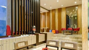A modern hotel lobby with a reception desk, seating area, and a buffet. - Almadera Hotel Makassar (Makassar)