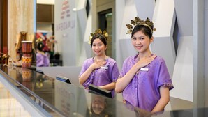 Receptionists in purple uniforms standing at a glass counter with a modern interior design, including a visible sign with text. - Almadera Hotel Makassar (Makassar)