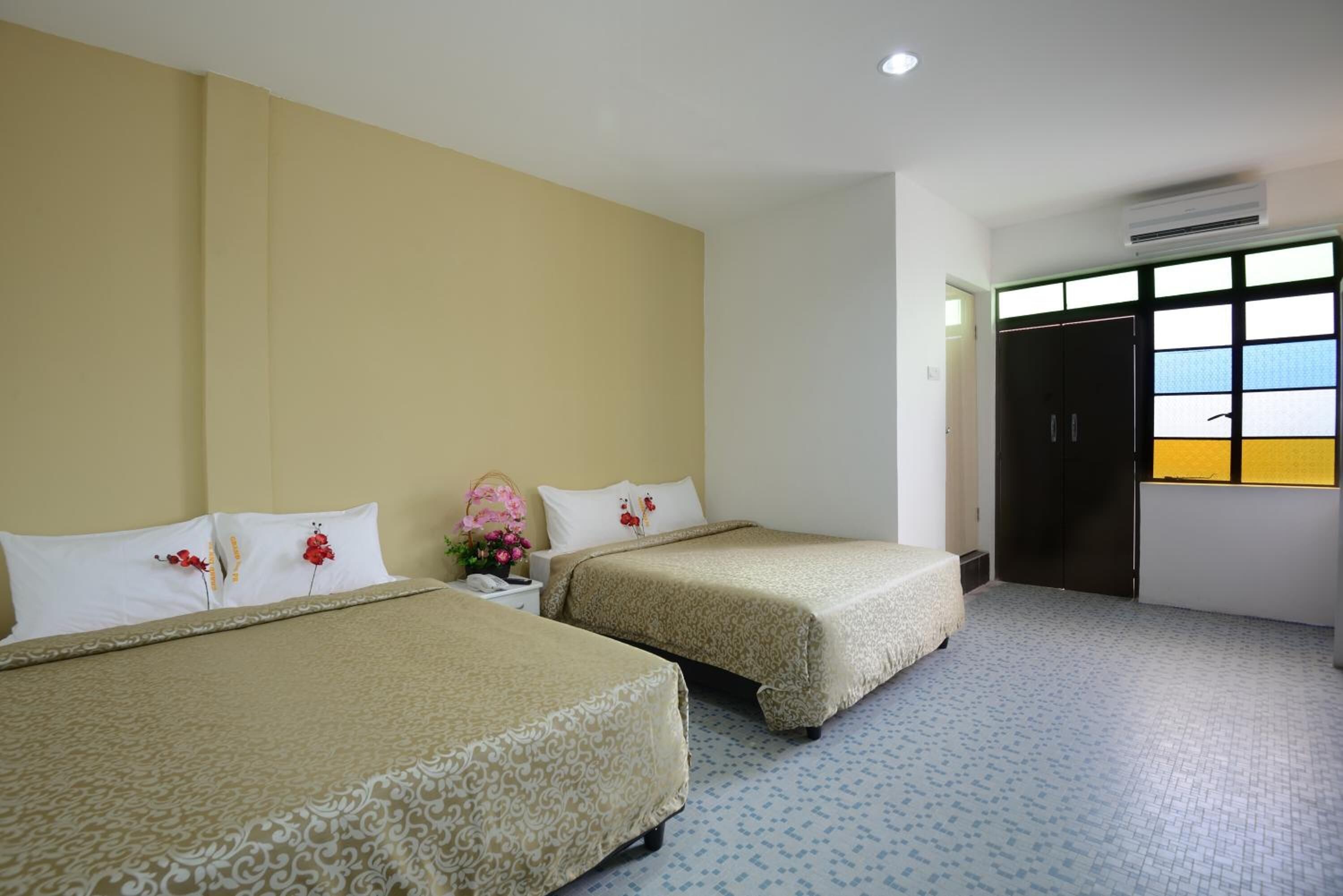 A hotel room with two beds, a small table with a phone, and a window with a view of the outside.