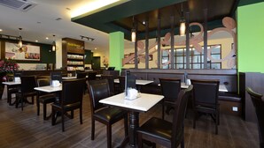 A restaurant interior with booths and tables, a counter with a menu, and a decorative wall. - Grand Inn Penang Road (George Town)