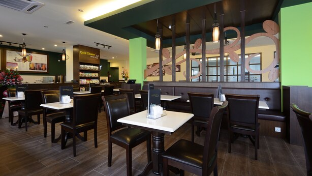 L’intérieur d’un restaurant avec des banquettes et des tables, un comptoir où figure le menu, et un mur décoratif.