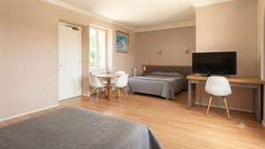 Een slaapkamer met een bed, bureau met stoel, televisie en raam.