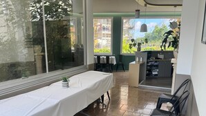 Een kamer met een lange tafel, stoelen, een receptiebalie en uitzicht op buiten.