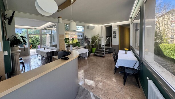 Een moderne hotellobby met een receptiebalie, een zithoek en grote ramen met uitzicht op de omgeving.