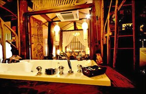 A bathroom with a large bathtub, a sink, and a mirror. There are decorative lights and a curtain. - Fern Paradise (San Sai)