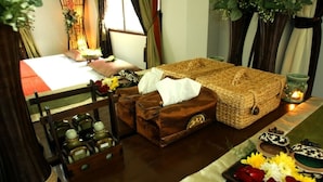 A room with a bed, a wicker sofa, a small table with candles, and a tray with flowers. - Naruncha Green House (Chiang Mai)