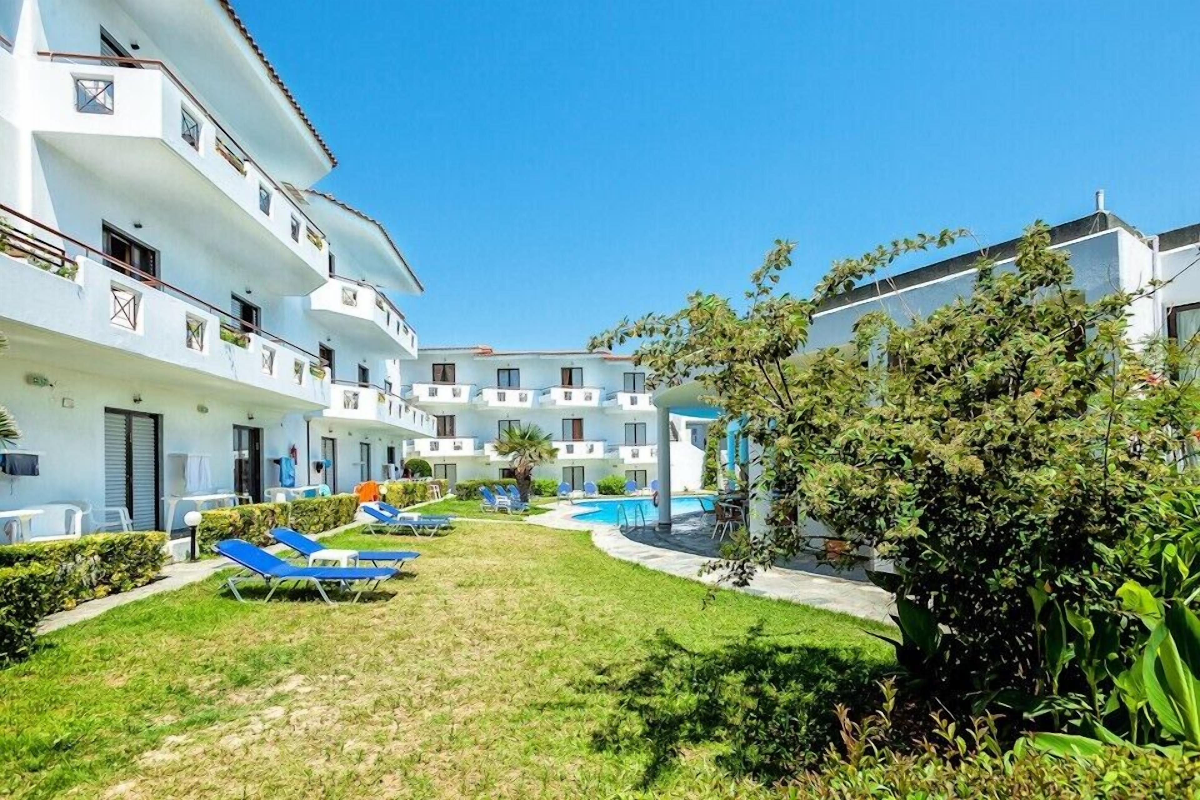 A courtyard with a swimming pool, lounge chairs, and a building with multiple balconies.
