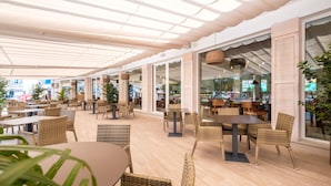 An indoor dining area with wicker furniture, large windows, and a ceiling with natural light. - Plaza Santa Ponsa Boutique Hotel - Adults Only (Calvia)