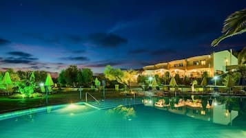 Una piscina techada, una piscina al aire libre, sombrillas