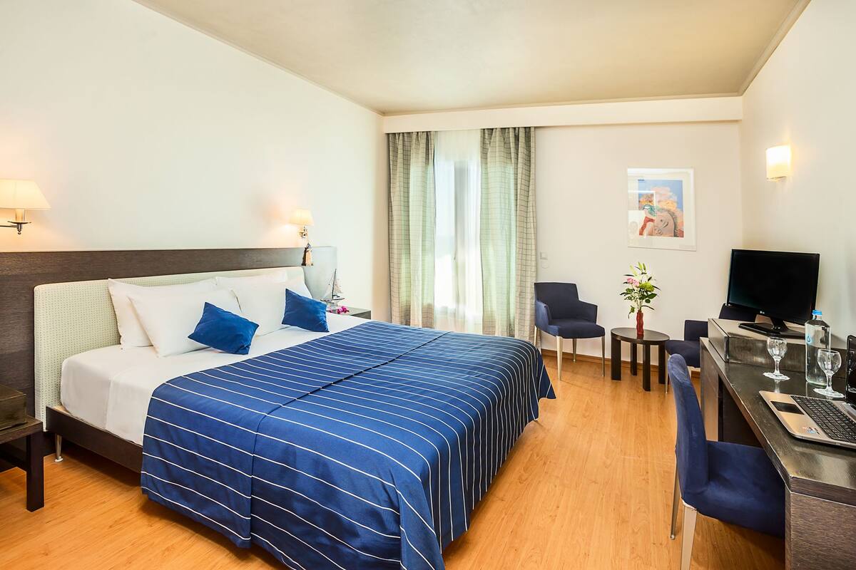 A hotel room with a bed, desk, chair, and a television.