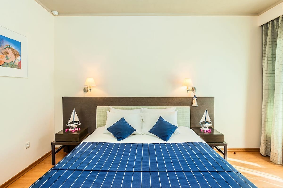 A neatly made bed with a blue-striped bedspread, two matching pillows, and two bedside tables with lamps and small decorative items.