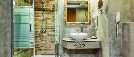 Un baño moderno con cabina de ducha curva, tocador con un espejo grande y un inodoro.