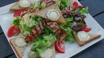 A plate of food consisting of toasted bread, bacon, lettuce, tomatoes, and cheese.