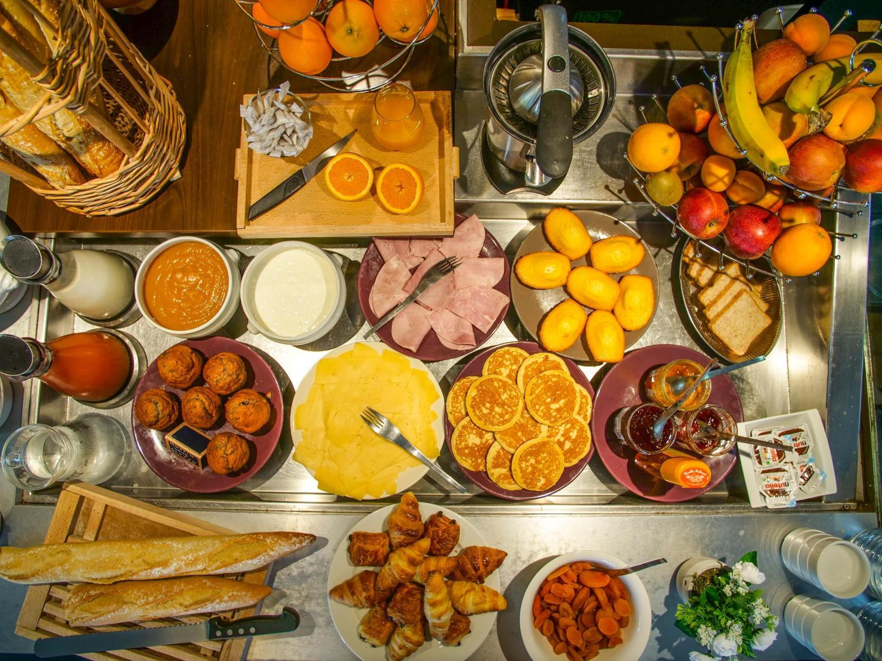 Un bufé con diversos alimentos, entre ellos frutas, pasteles y salsas.