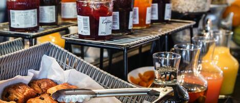 A breakfast buffet with pastries, jams, and juices.