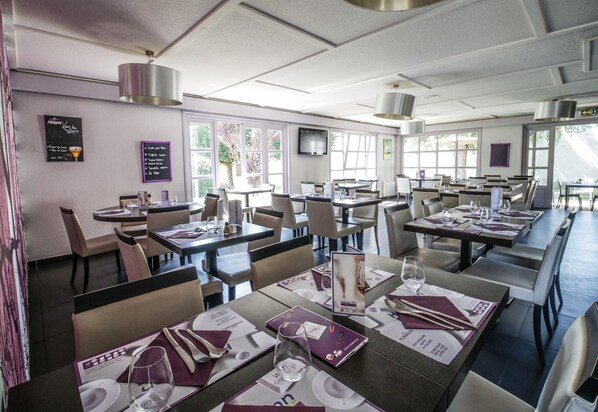 Un restaurante con varias mesas y sillas, un menú y un televisor en la pared.