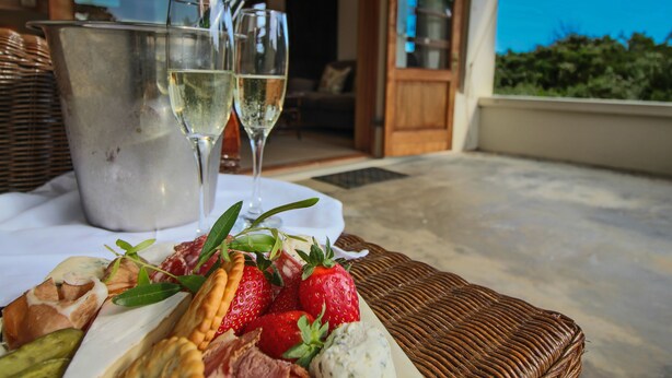 A table with a charcuterie board, two glasses of white wine, and a metal bucket. - Dune Ridge Country House (Saint Francis Bay)