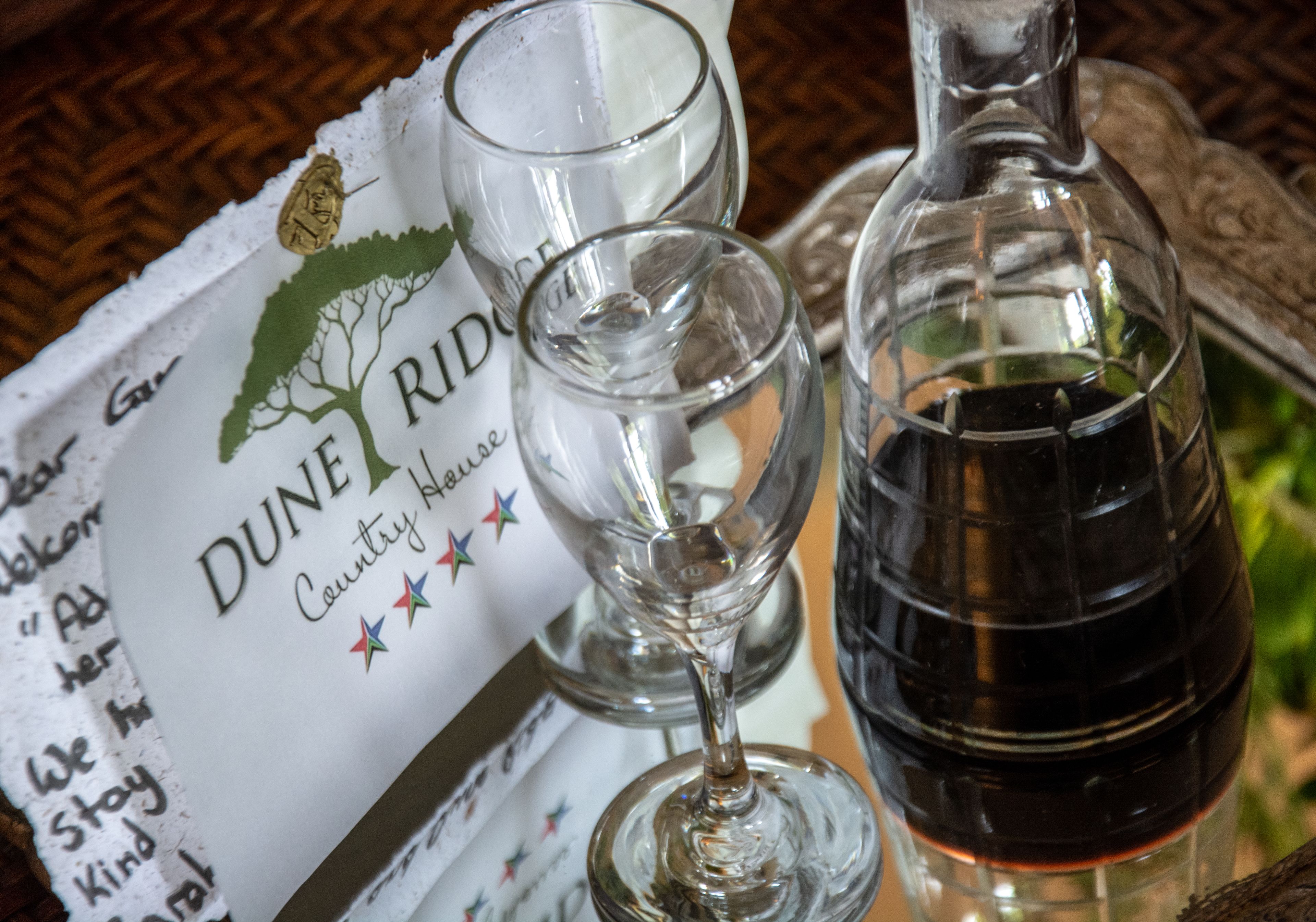 A menu with a logo and text, two empty wine glasses, and a bottle of red wine on a table.