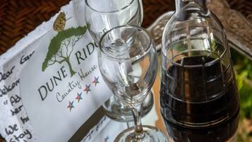 A menu with a logo and text, two empty wine glasses, and a bottle of red wine on a table.