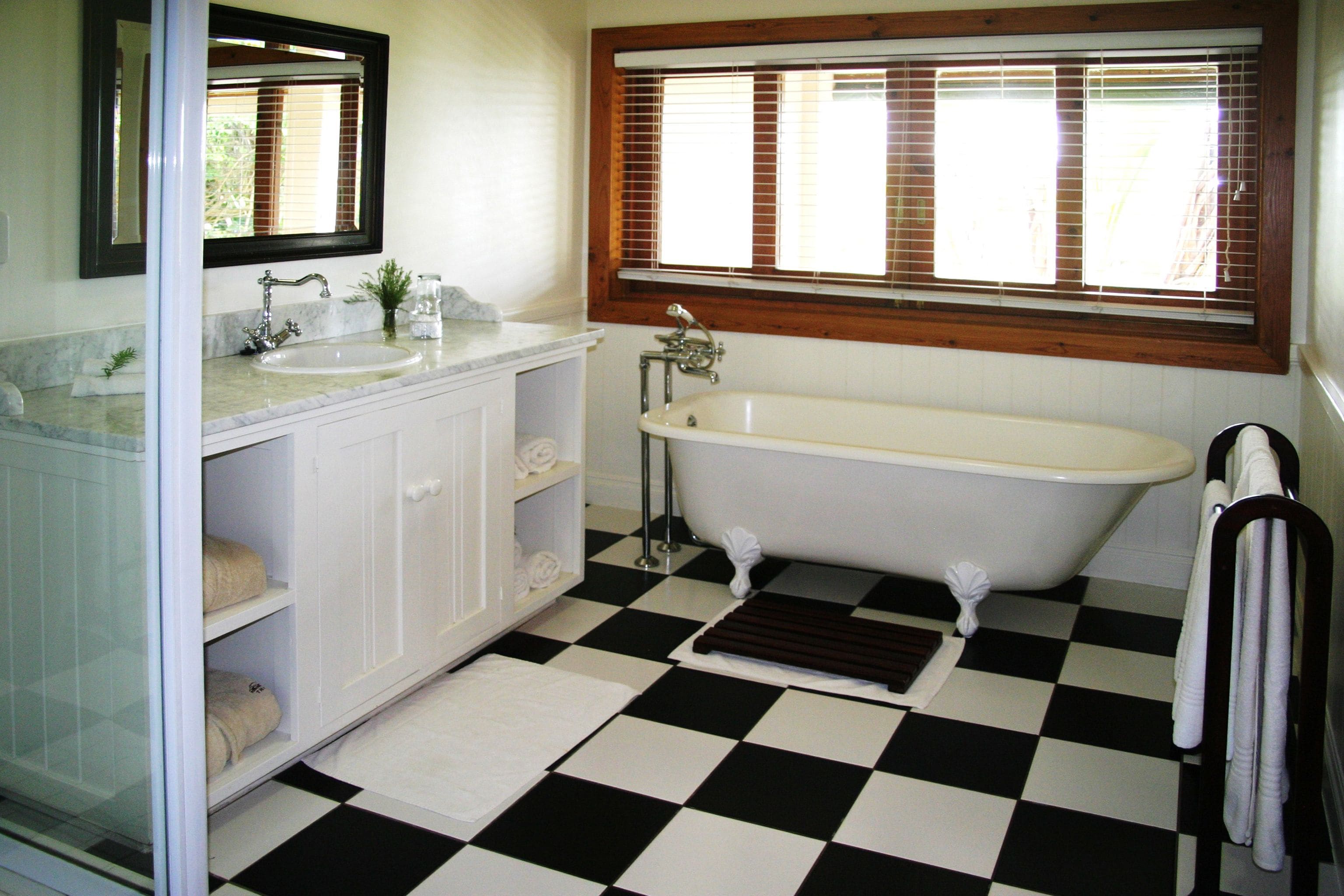 A bathroom with a checkered floor, a white bathtub, a sink, and a mirror above the sink.