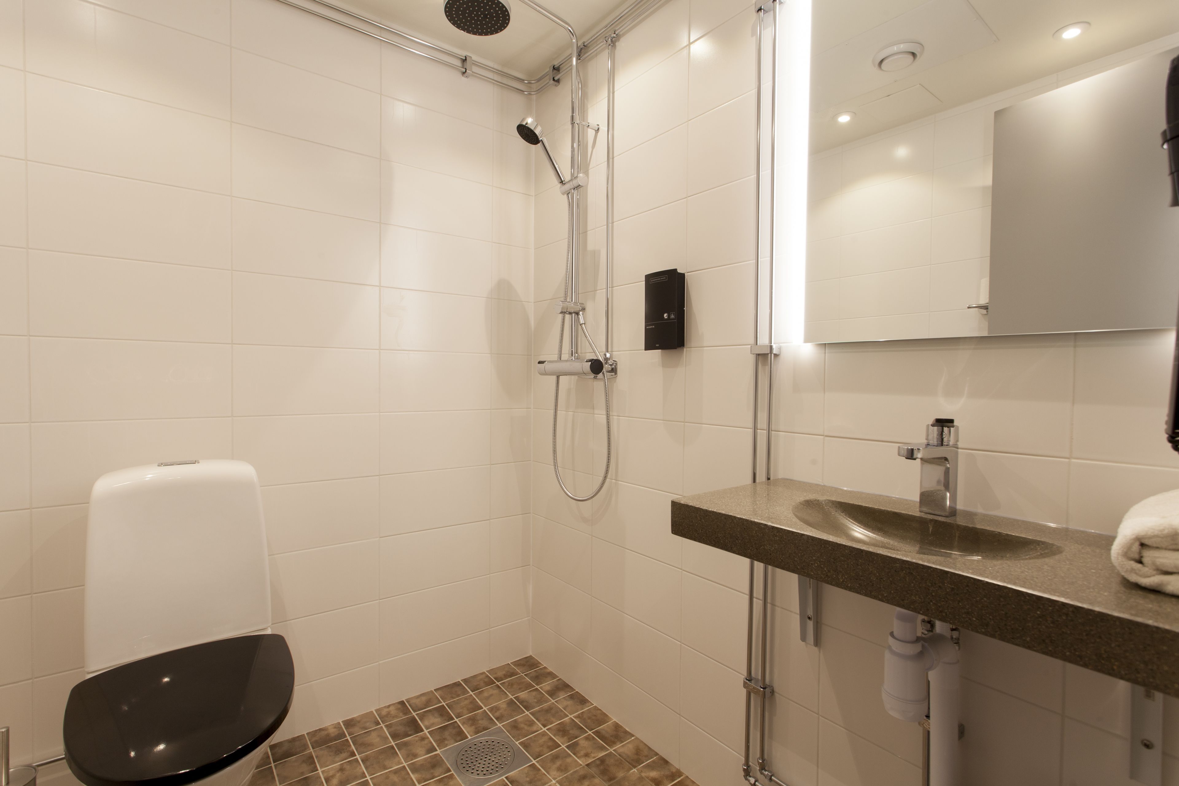 A modern bathroom with a shower, toilet, and sink.