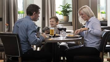 A family dining at a round table with a view of a cityscape through large windows.