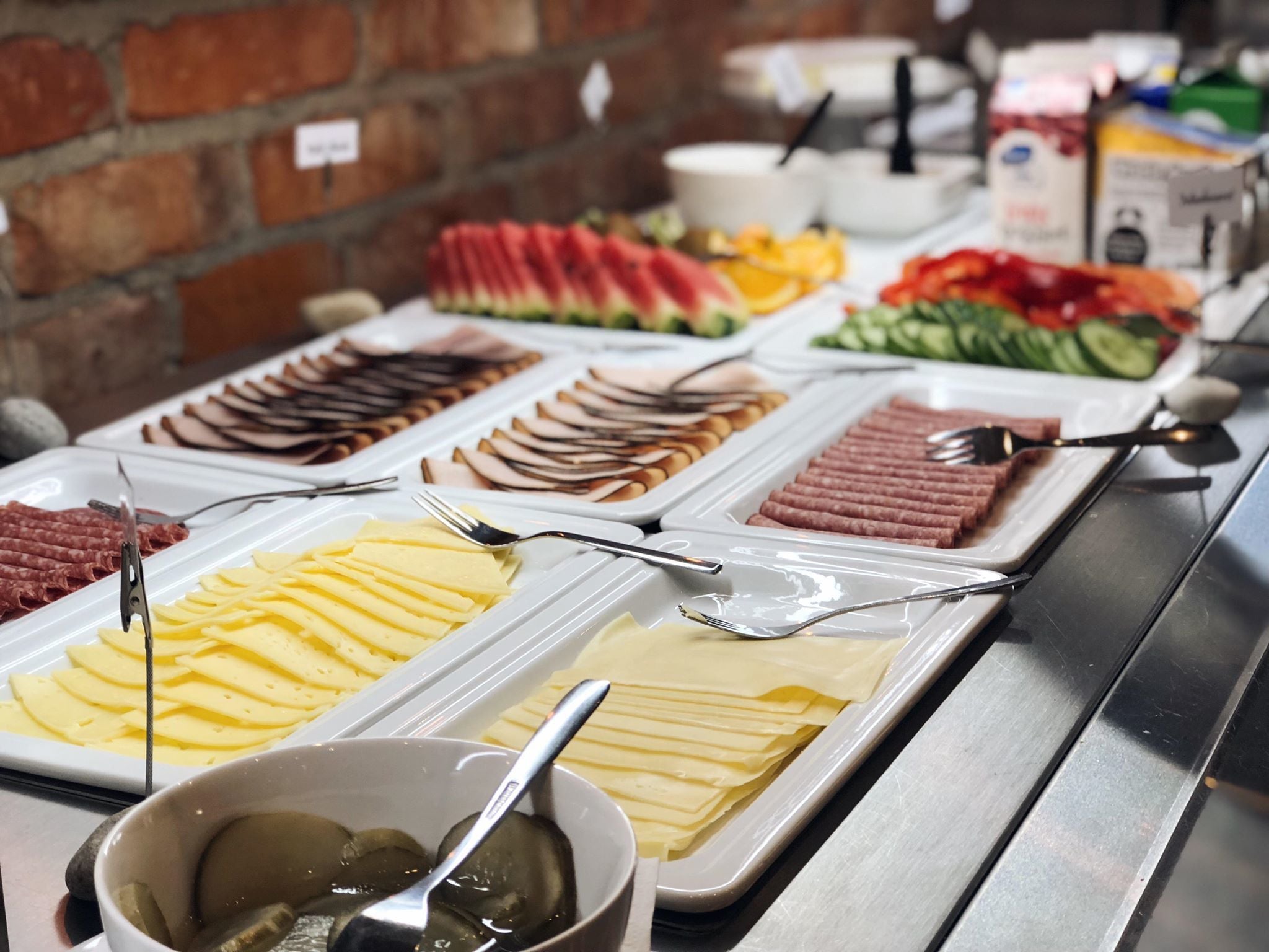 A buffet with various food items including sliced meats, cheeses, and fruits.