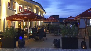 An outdoor seating area with tables and chairs, umbrellas, and potted plants. - Hotell Nordic (Norrköping)